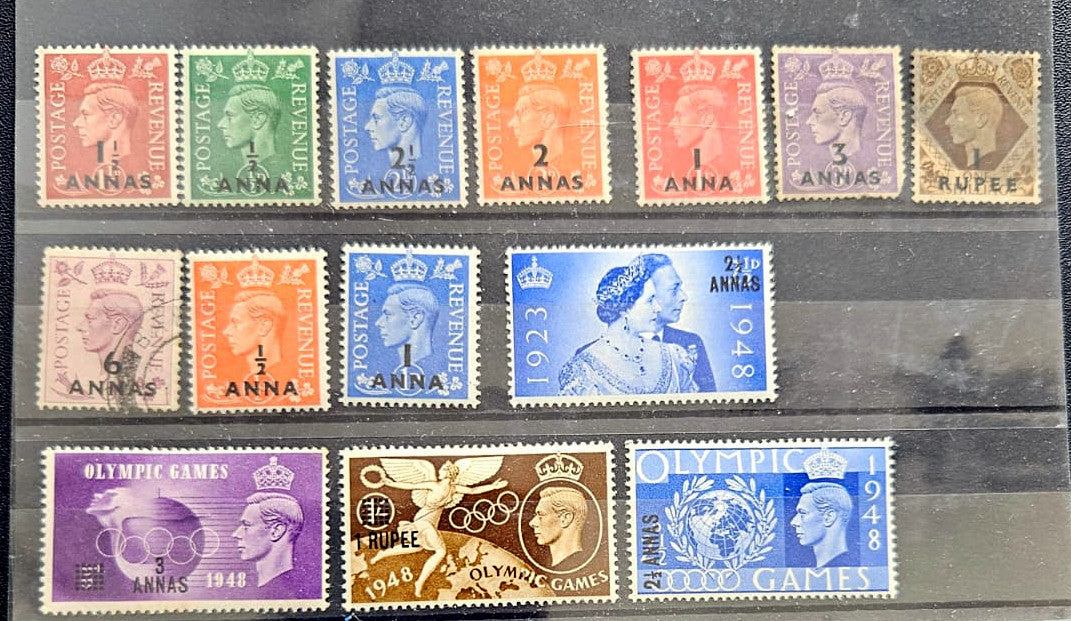 A set of twelve vintage British Rupee stamps from 1936 to 1948, arranged in three rows on a dark display card. The stamps feature various colors including green, blue, orange, red, purple, and brown, with Queen Elizabeth II and the Olympic Games motifs.