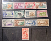 A collection of vintage Pitcairn Islands postage stamps arranged on a dark wooden surface, with a single red stamp placed below the group.