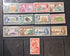 A collection of vintage Pitcairn Islands postage stamps arranged on a dark wooden surface, with a single red stamp placed below the group.