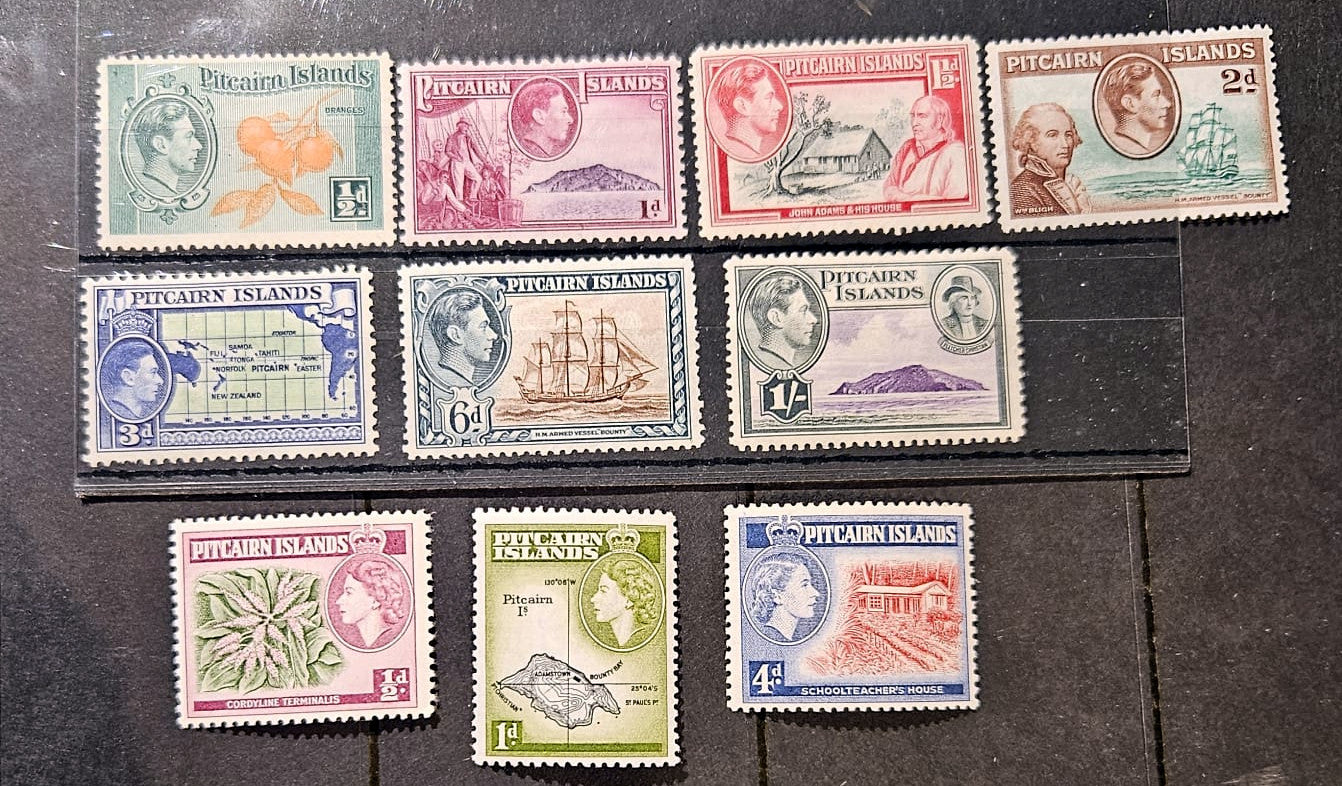 A set of ten vintage Pitcairn Islands postage stamps from 1956, displayed on a dark textured background. The stamps feature various colors including green, pink, red, blue, and yellow, with designs depicting local landmarks, flora, and fauna.
