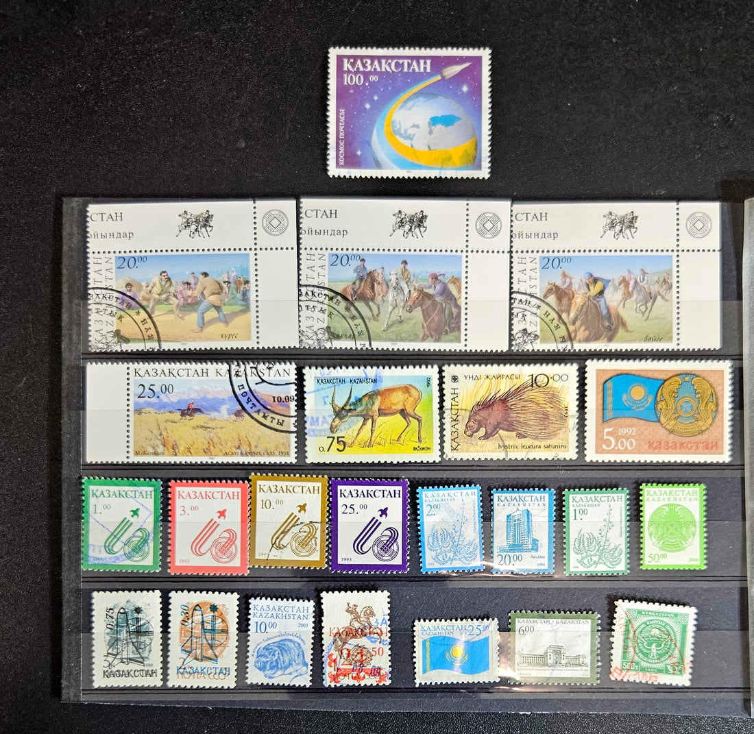 A collection of various Kazakhstan postage stamps displayed in a row, showcasing different designs and colors.