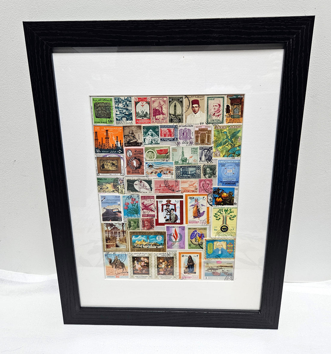 Framed collage of various Arab postage stamps with a black frame.