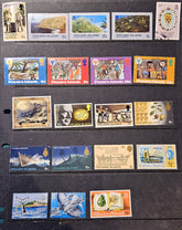 A collection of vintage Pitcairn Islands postage stamps arranged on a black display card, showing various landscapes, figures, and scenes with different colors and denominations.