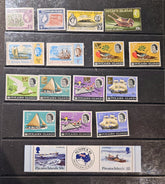 A collection of vintage Pitcairn Islands postage stamps arranged on a dark wooden surface, including various single stamp pieces and a horizontal strip of stamps.