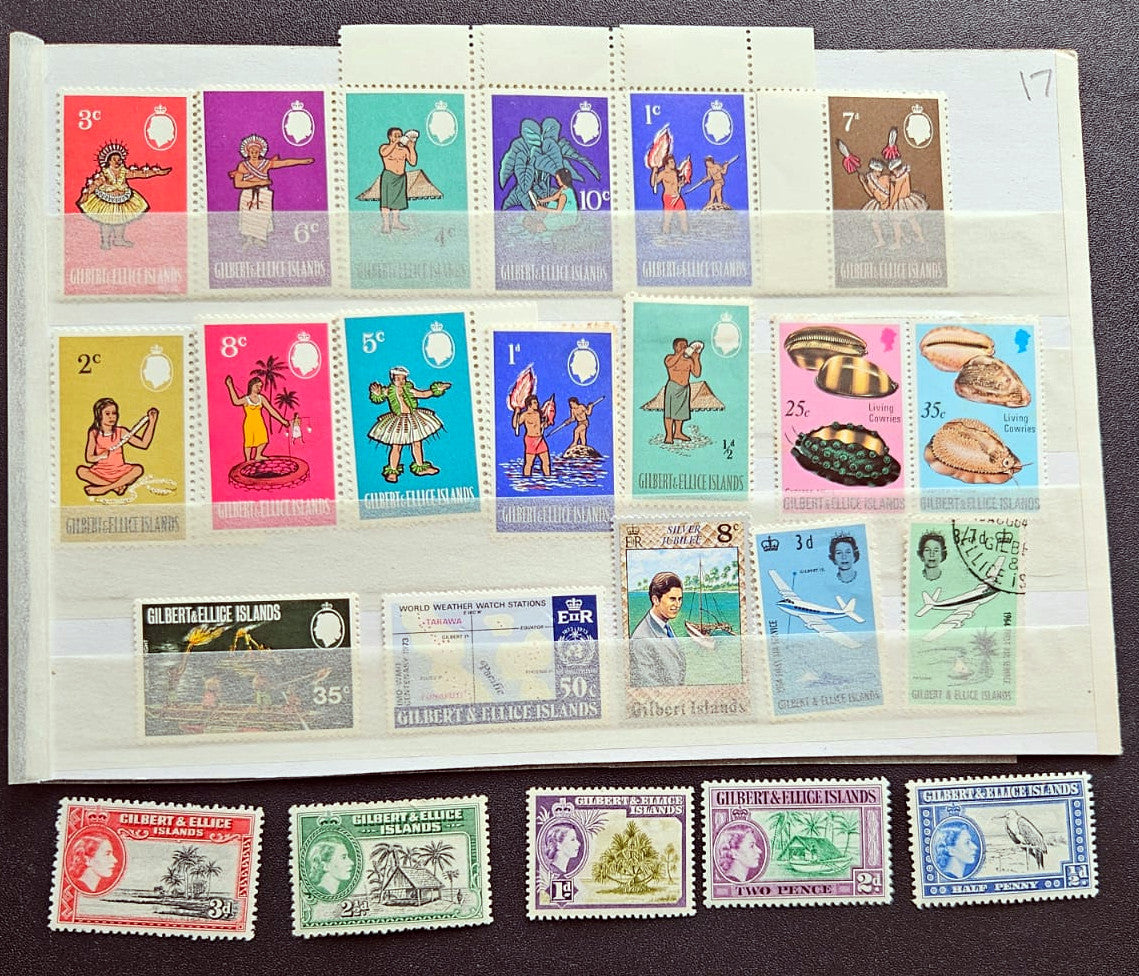 A collection of vintage Gilbert Islands postage stamps displayed on a white mounting sheet, with several individual stamps arranged below on a dark surface.