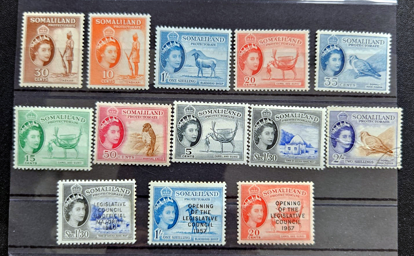 A set of twelve vintage Somalia postage stamps arranged in a 3-by-4 grid on a black background. The stamps feature various colors including blue, orange, green, pink, and gray, with Queen Elizabeth II depicted on each stamp.