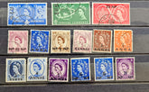 A set of twelve vintage Queen Elizabeth II British colony postage stamps from 1957, arranged in three rows on a stack