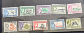 A set of twelve vintage Gilbert postage stamps displayed on a dark gray background, featuring various colors and designs from 1956.