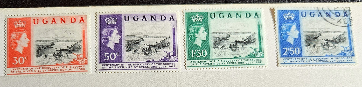 A collection of British Commonwealth Uganda stamps from various monarchs displayed on a surface.