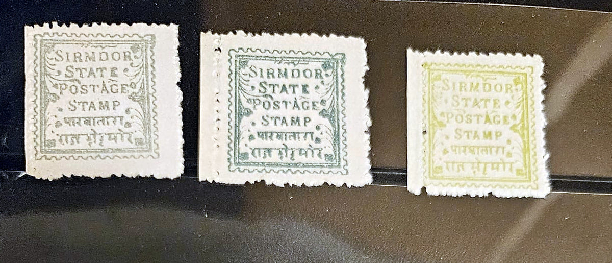 Three vintage Sirmdor State postage stamps displayed side by side on a dark reflective surface. The left stamp is light gray, the middle is greenish-gray, and the right is pale yellow, each with the text &
