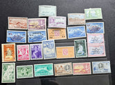 A collection of vintage Tonga postage stamps arranged in rows on a dark surface. The stamps feature various colors and denominations, including blue, green, orange, pink, and purple, with some showing portraits and landscapes.