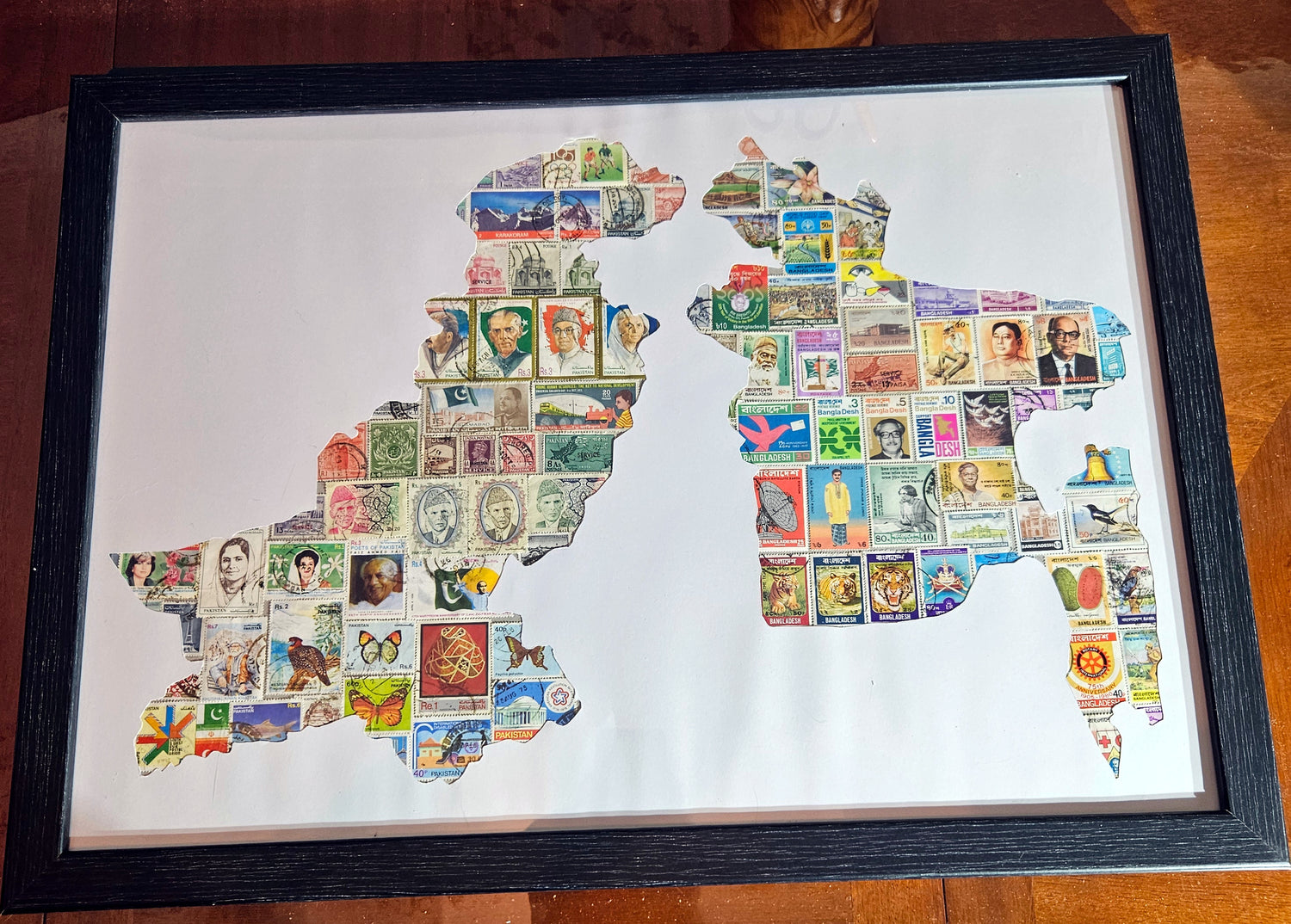 Framed map of bangladesh and pakistan,  made from postage stamps on a wooden surfacea