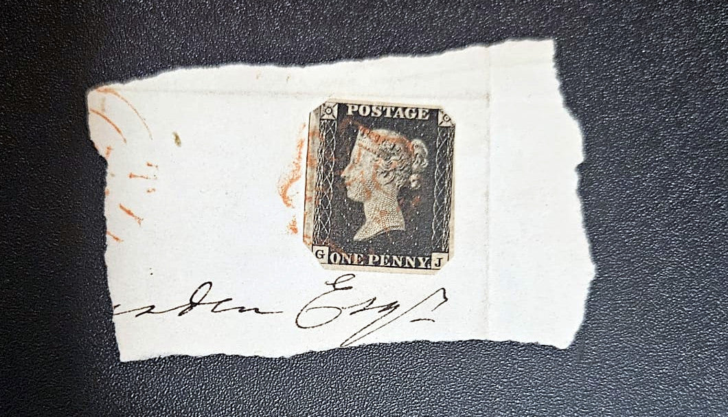 QV Penny black stamp on a piece of paper with a signature, on a dark background