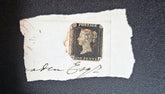 QV Penny black stamp on a piece of paper with a signature, on a dark background