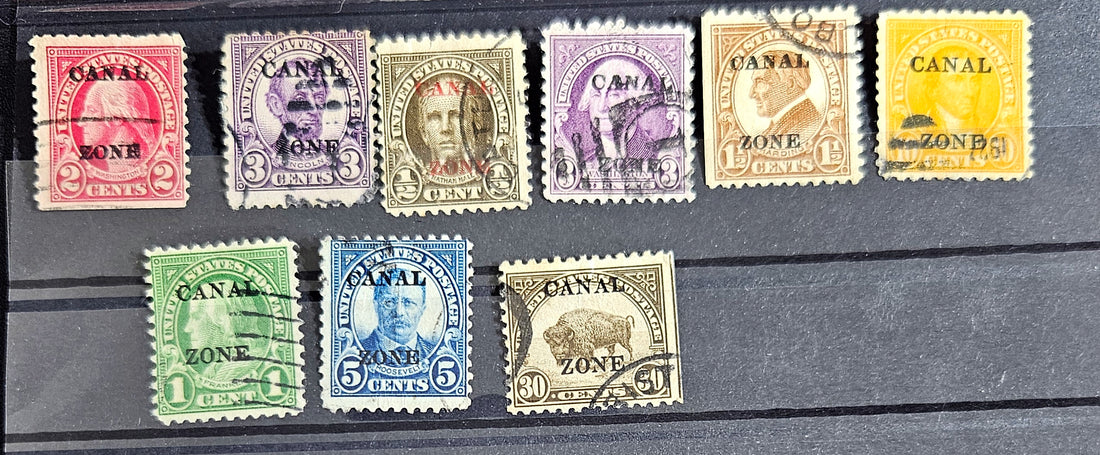 A collection of vintage postage stamps from the Panama Canal Zone, featuring various colors and designs, some with over-printed text.