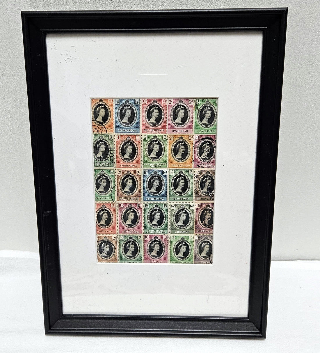 Framed print of vintage postage stamps with Queen Elizabeth portrait designs on a white background