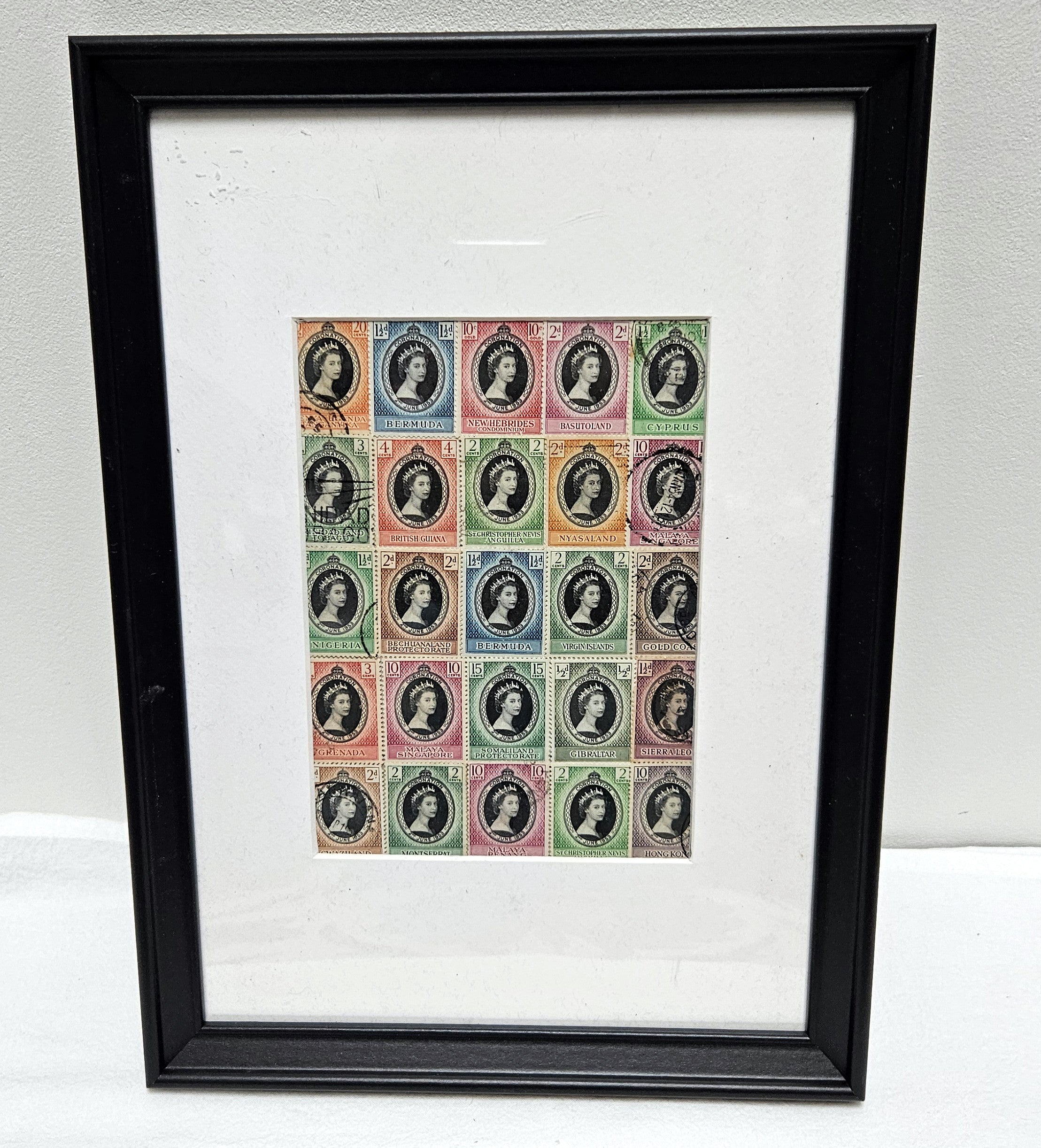 Framed print of vintage postage stamps with Queen Elizabeth portrait designs on a white background
