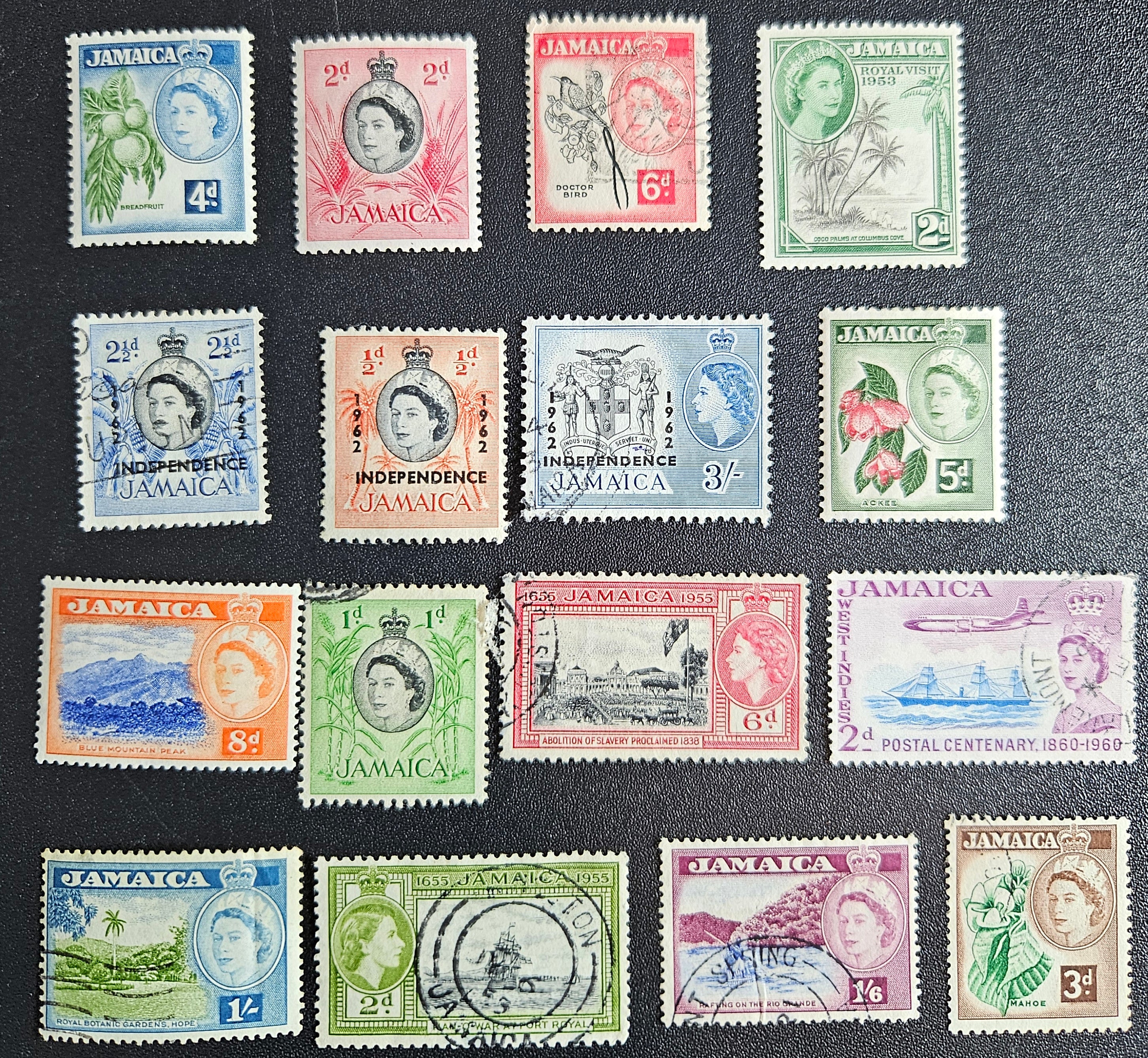 A collection of vintage Jamaica stamps from various reigns of British monarchs, displayed on a black background.