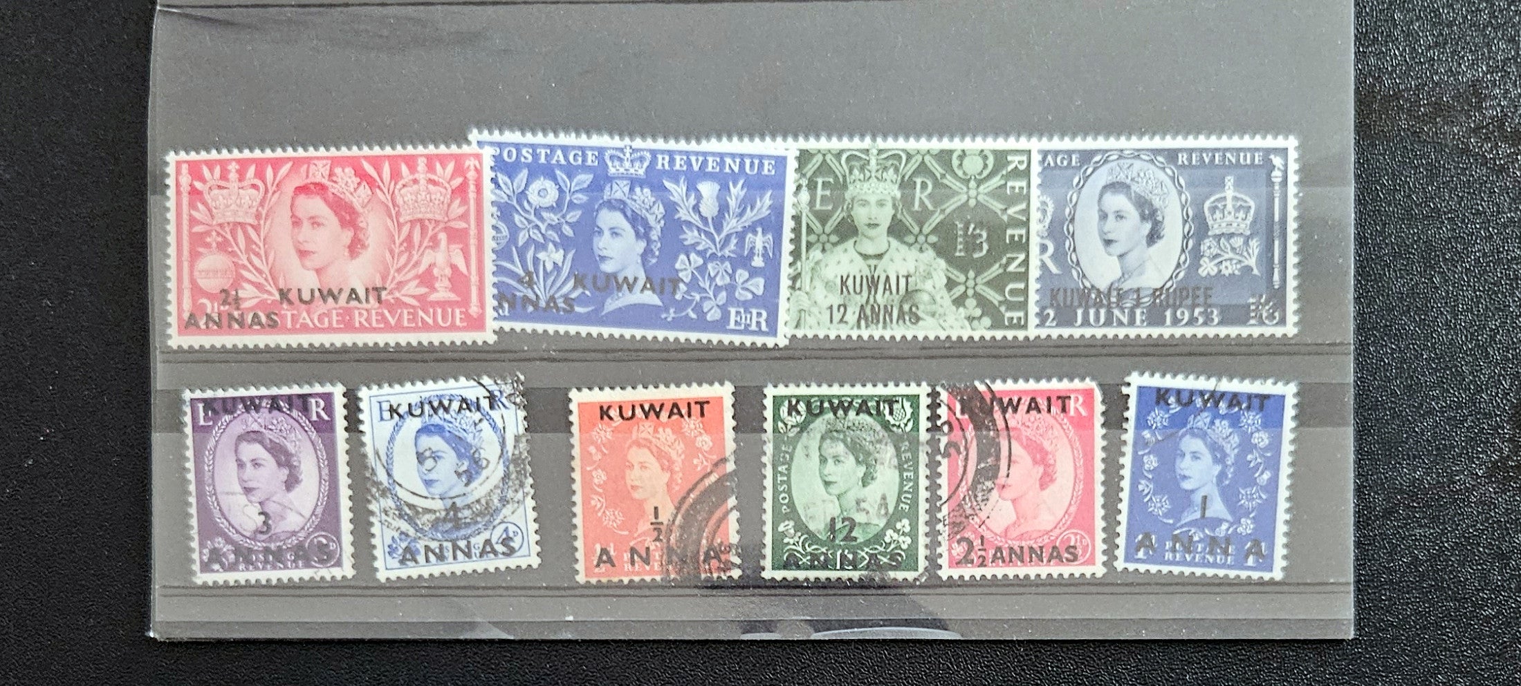 Collection of vintage stamps from Kuwait in a display case.