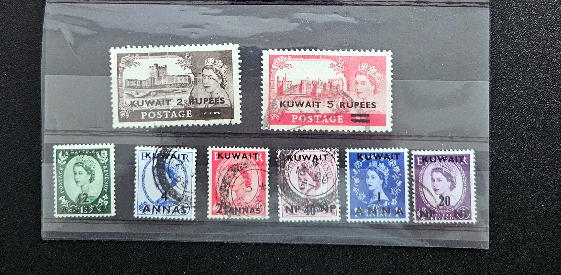 Collection of vintage Kuwait postage stamps in a display case.