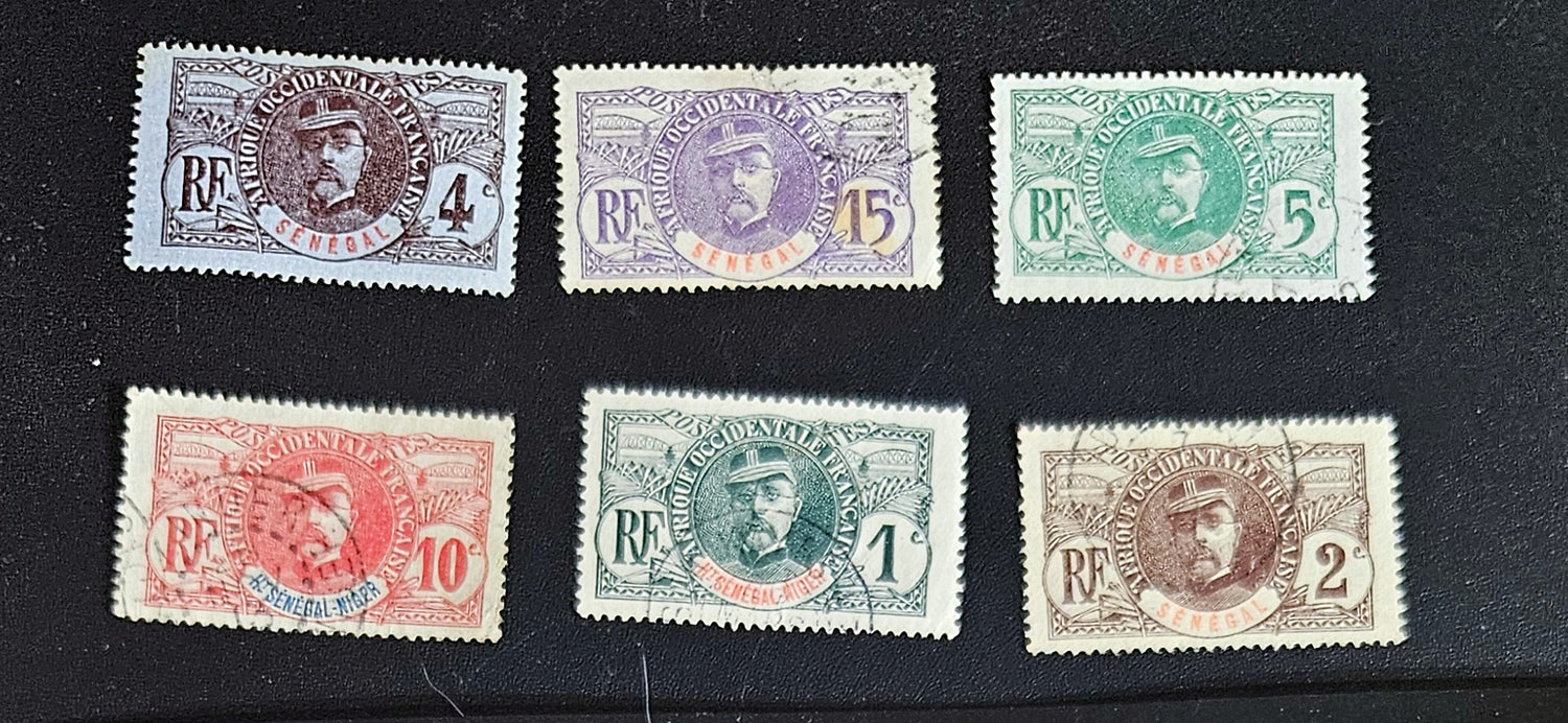 A set of eight vintage stamps from French Senegal with various designs and denominations displayed against a black background.