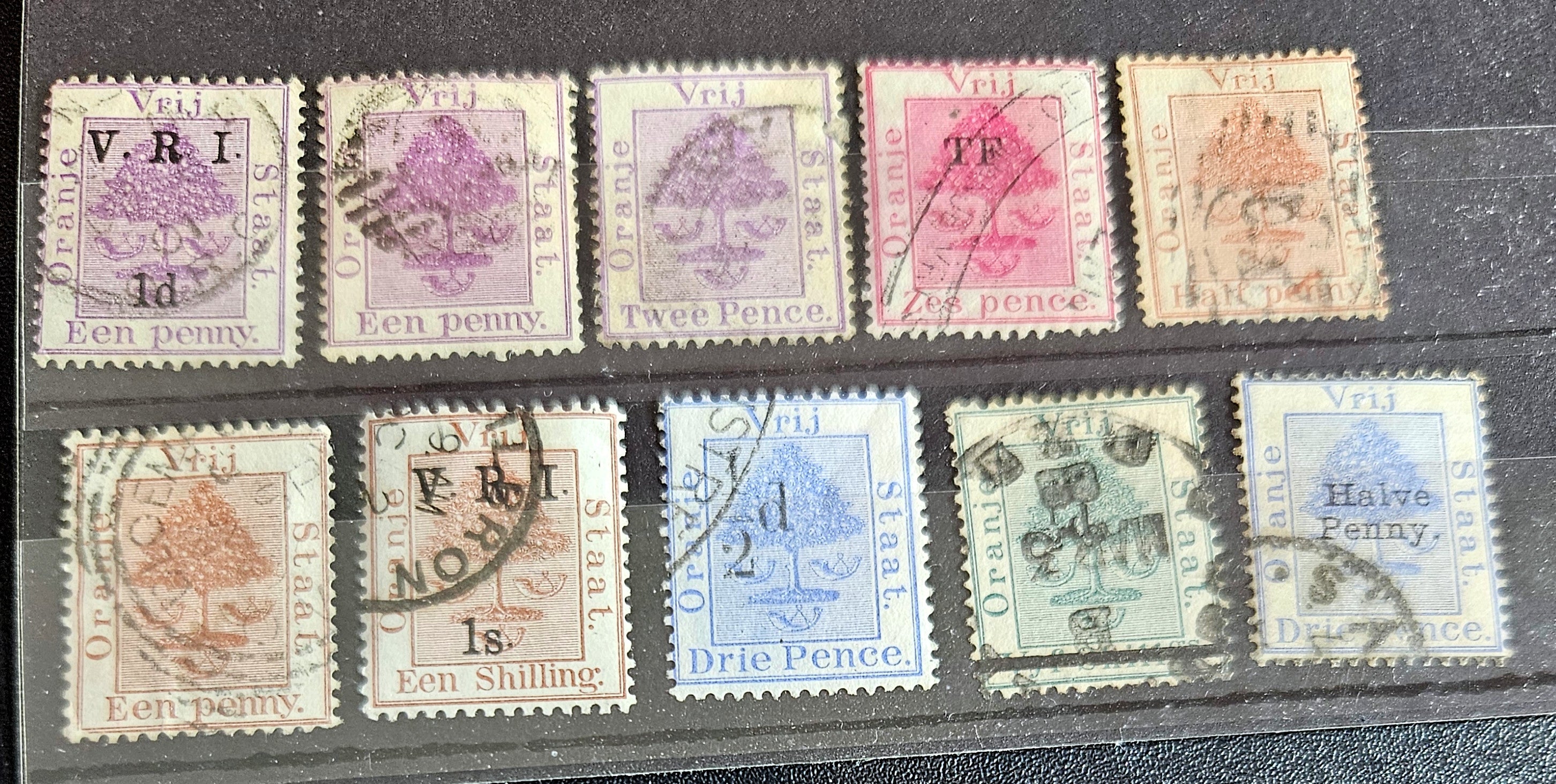 A collection of vintage postage stamps from the Orange Free State, featuring various denominations and cancellation marks, housed in a plastic sleeve.