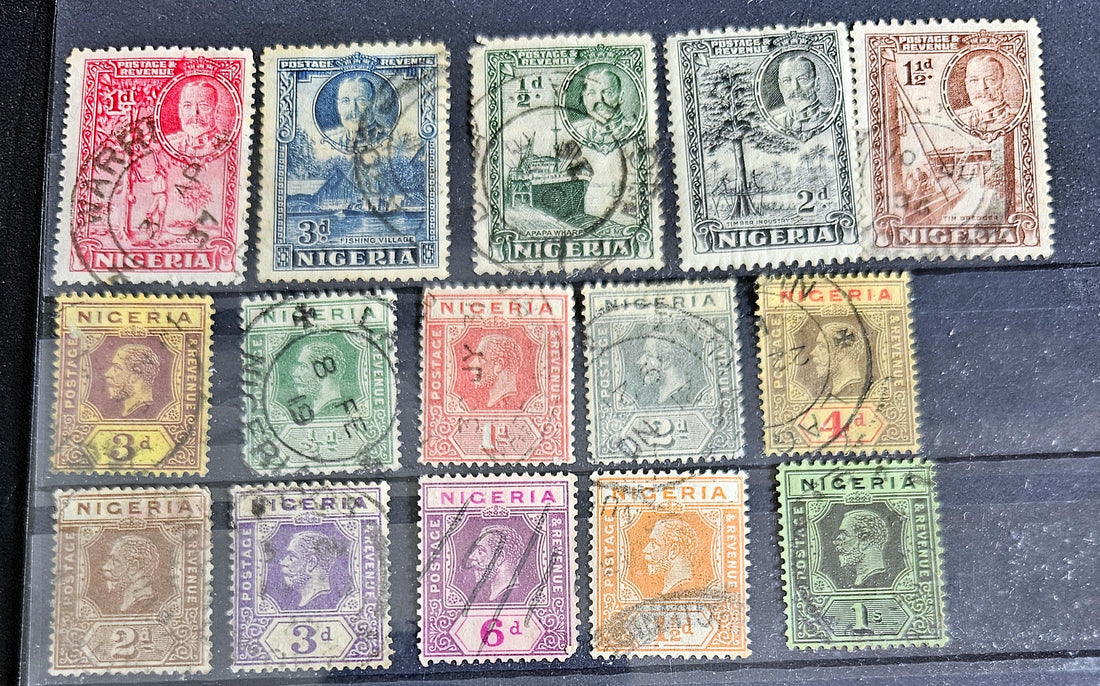 A collection of vintage British Nigeria stamps displayed on a surface, featuring various colors and motifs related to different eras in Nigerian history.
