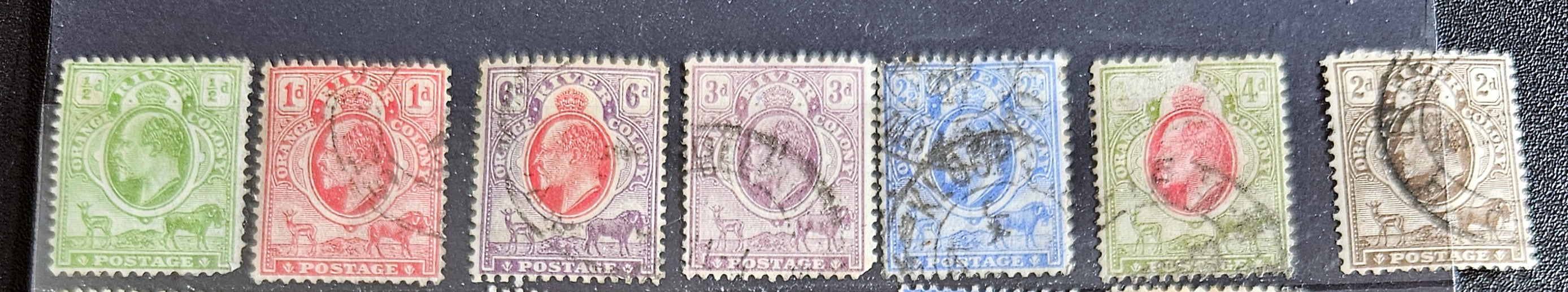 A collection of vintage postage stamps from the Orange Free State, featuring various denominations and cancellation marks, housed in a plastic sleeve.
