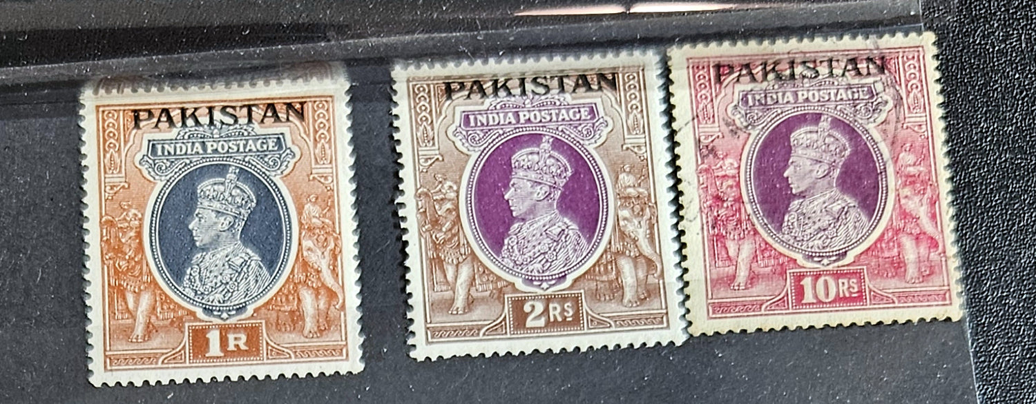 A collection of vintage Pakistan stamps from various periods, showing different designs and denominations, displayed on a glass surface.