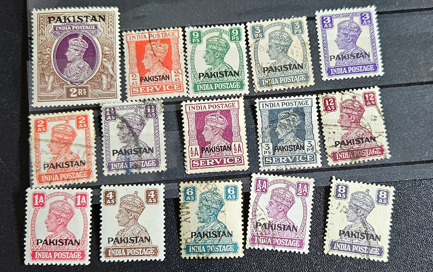 A collection of vintage Pakistan stamps from various periods, showing different designs and denominations, displayed on a glass surface.