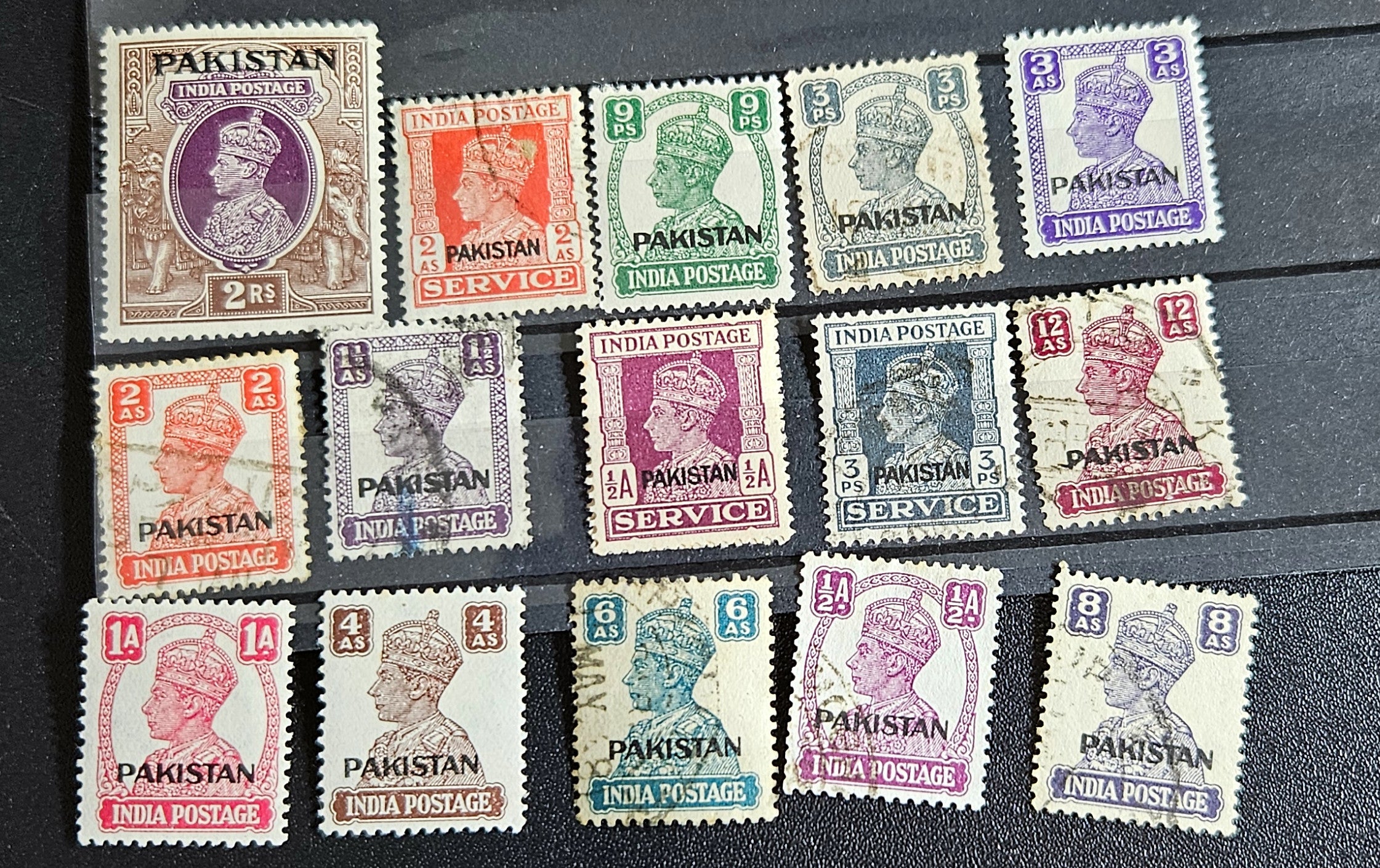 A collection of vintage Pakistan stamps from various periods, showing different designs and denominations, displayed on a glass surface.