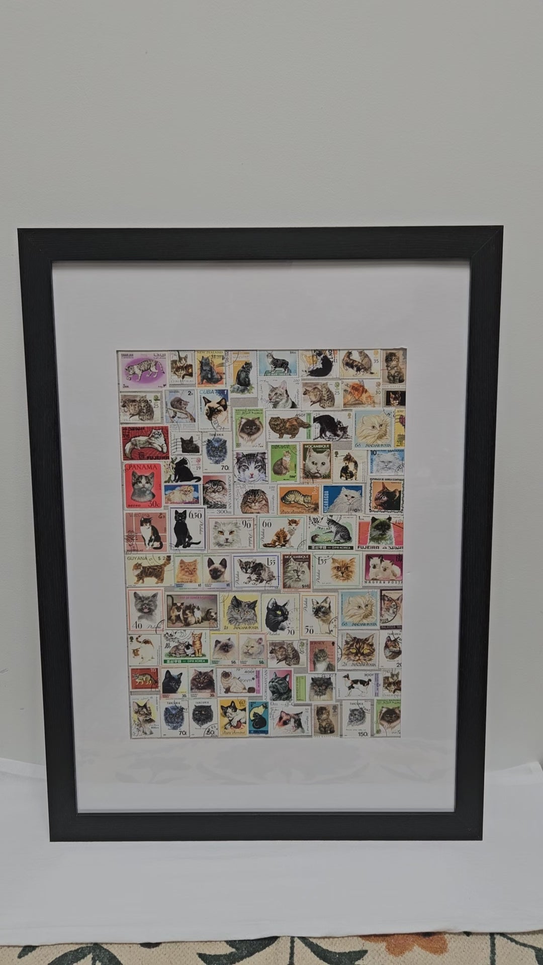 Framed collage of various cat stamps on a white background