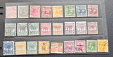 A collection of vintage Samoa postage stamps displayed in three horizontal rows on a clear plastic sleeve over a dark gray surface. The stamps feature various colors including green, pink, orange, blue, and yellow, with some showing cancellation marks.