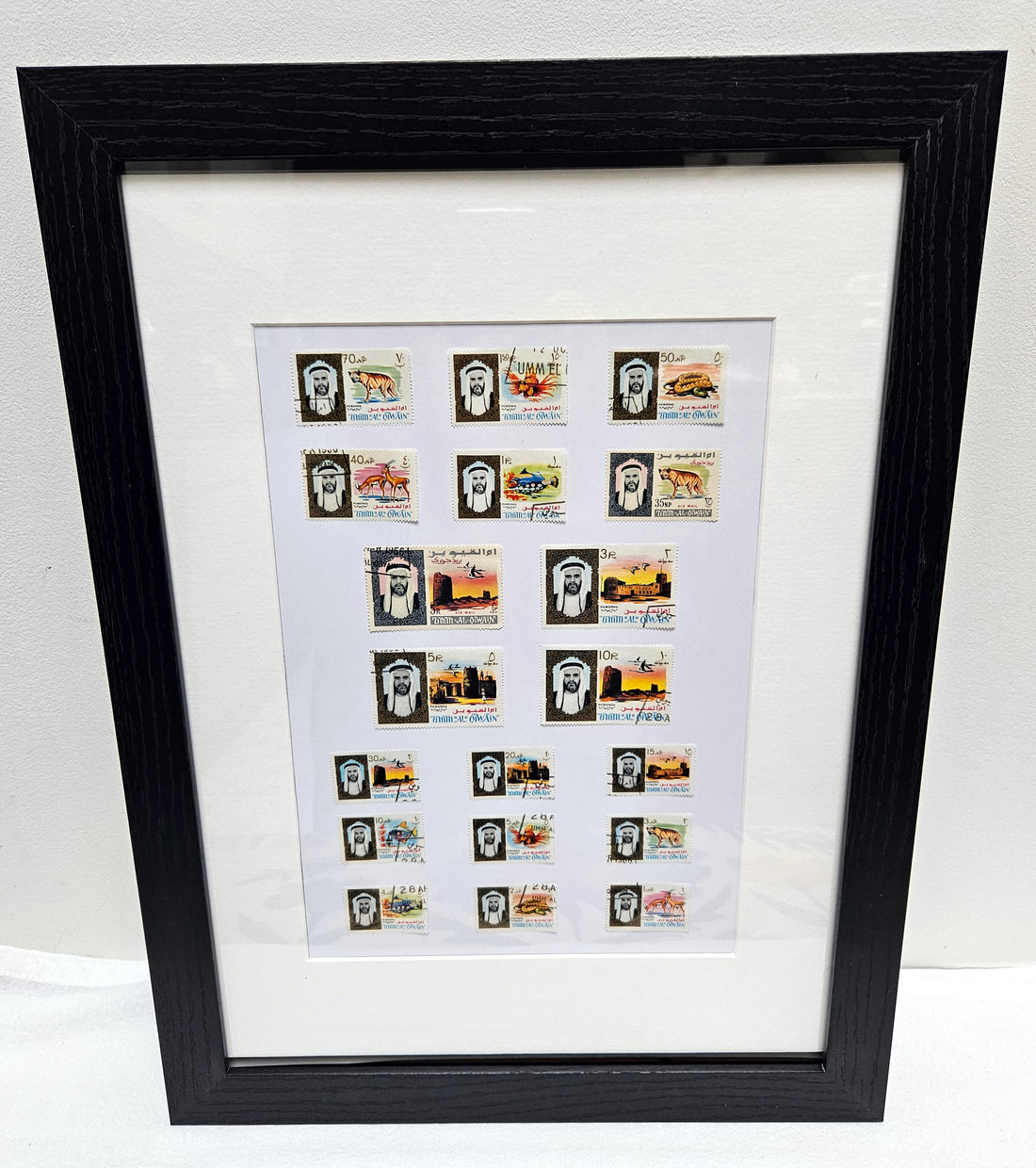 Framed collection of Umm Al Quwain stamps on a white background