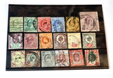 A collection of various vintage postage stamps arranged in a row, featuring different colors and designs, including shilling and pound sterling denominations.