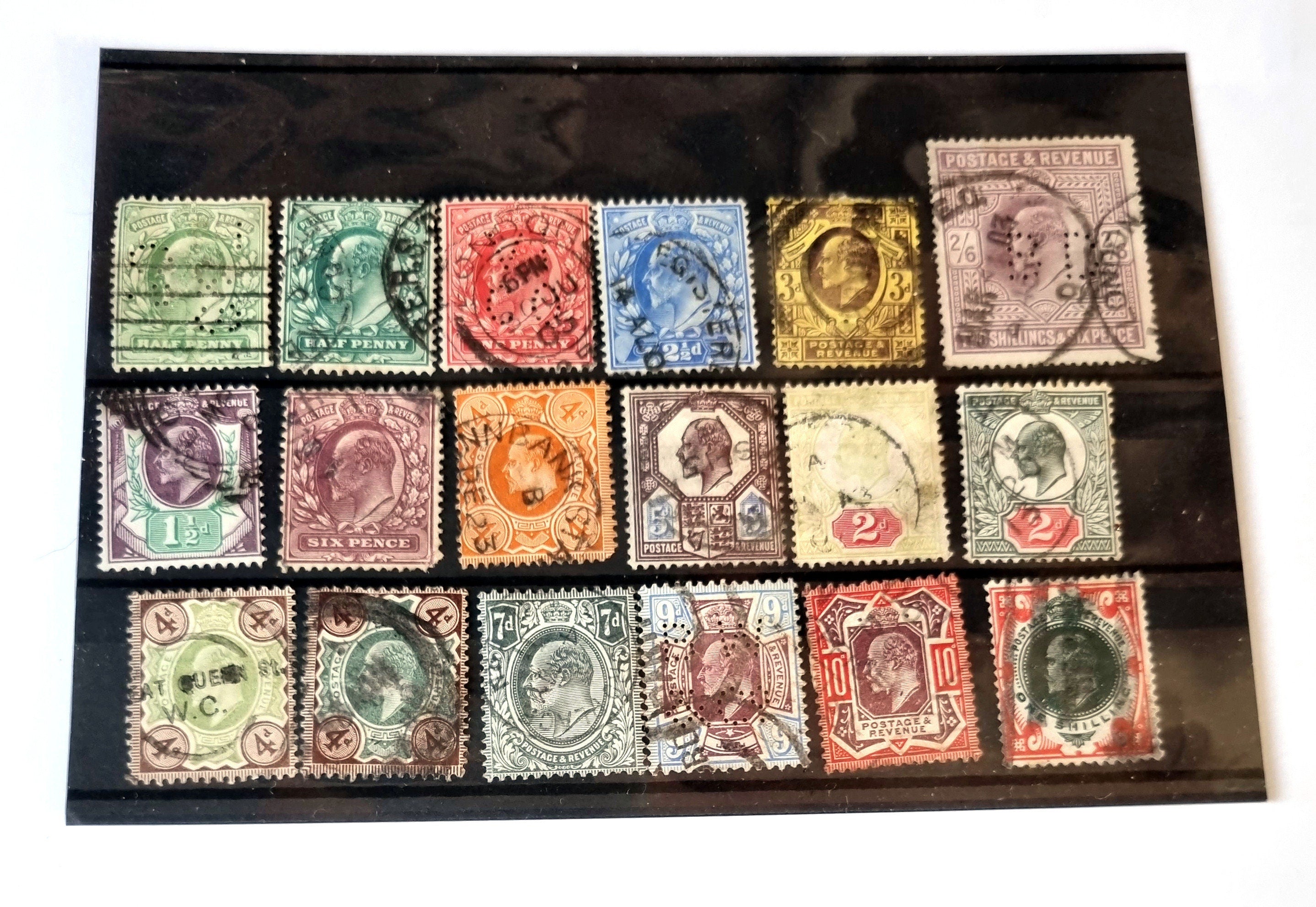 A collection of various vintage postage stamps arranged in a row, featuring different colors and designs, including shilling and pound sterling denominations.