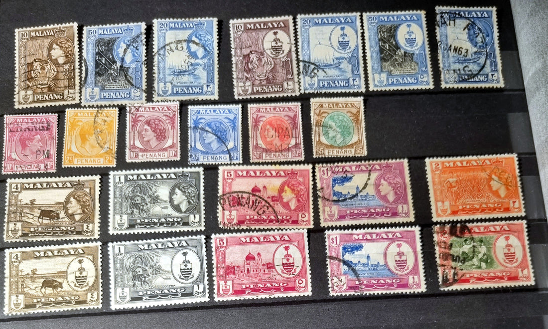 A collection of various vintage Malay state stamps laid out on a surface.