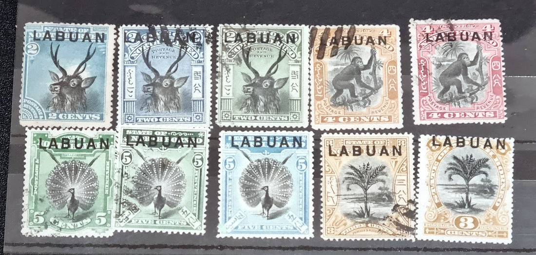A collection of six vintage Labuan postage stamps with various designs, predominantly in green, blue, and brown shades, featuring inscription &