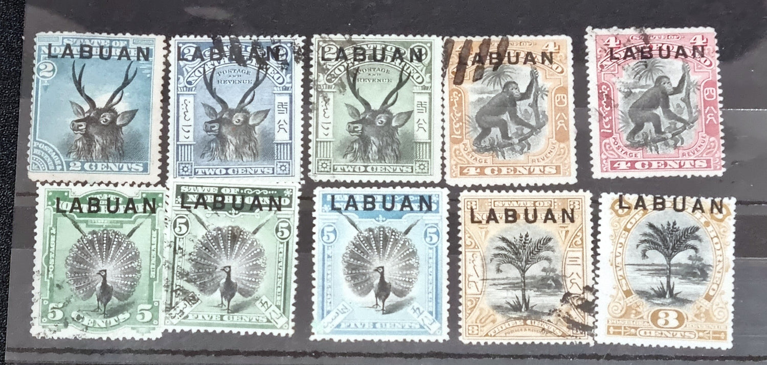 A collection of six vintage Labuan postage stamps with various designs, predominantly in green, blue, and brown shades, featuring inscription &