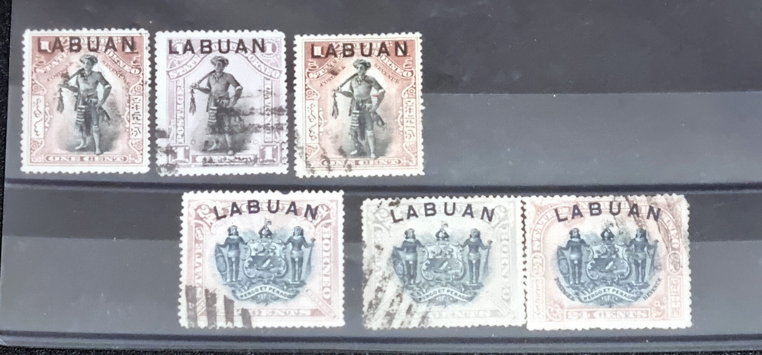 A collection of six vintage Labuan postage stamps with various designs, predominantly in green, blue, and brown shades, featuring inscription &