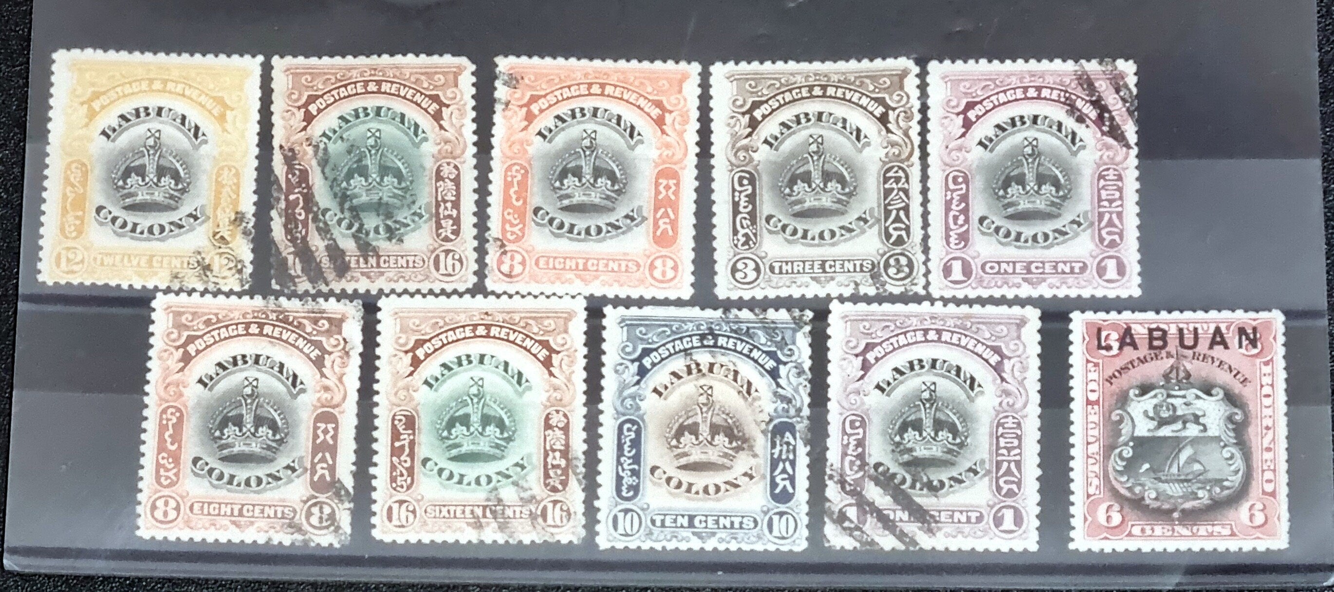 A collection of six vintage Labuan postage stamps with various designs, predominantly in green, blue, and brown shades, featuring inscription &
