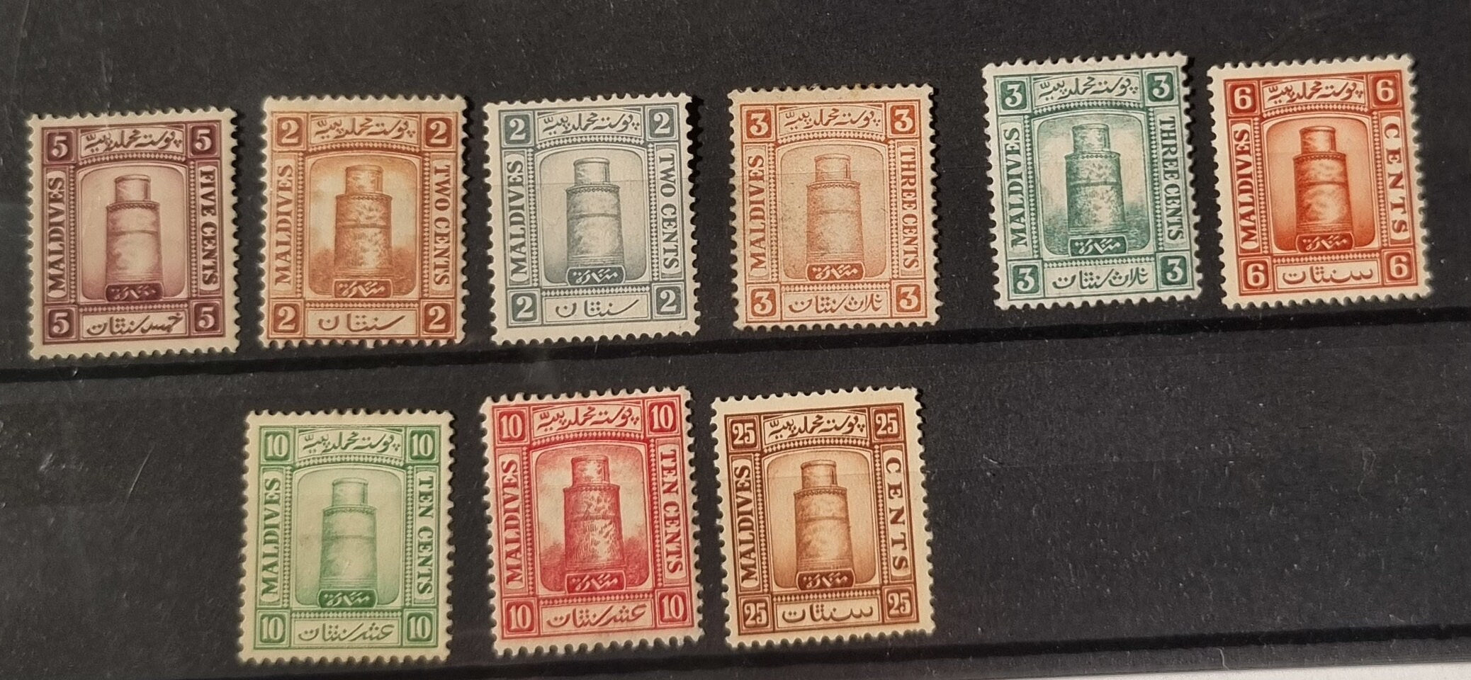 A collection of vintage postage stamps from Maldives Islands, featuring various designs and denominations, displayed on a dark background.