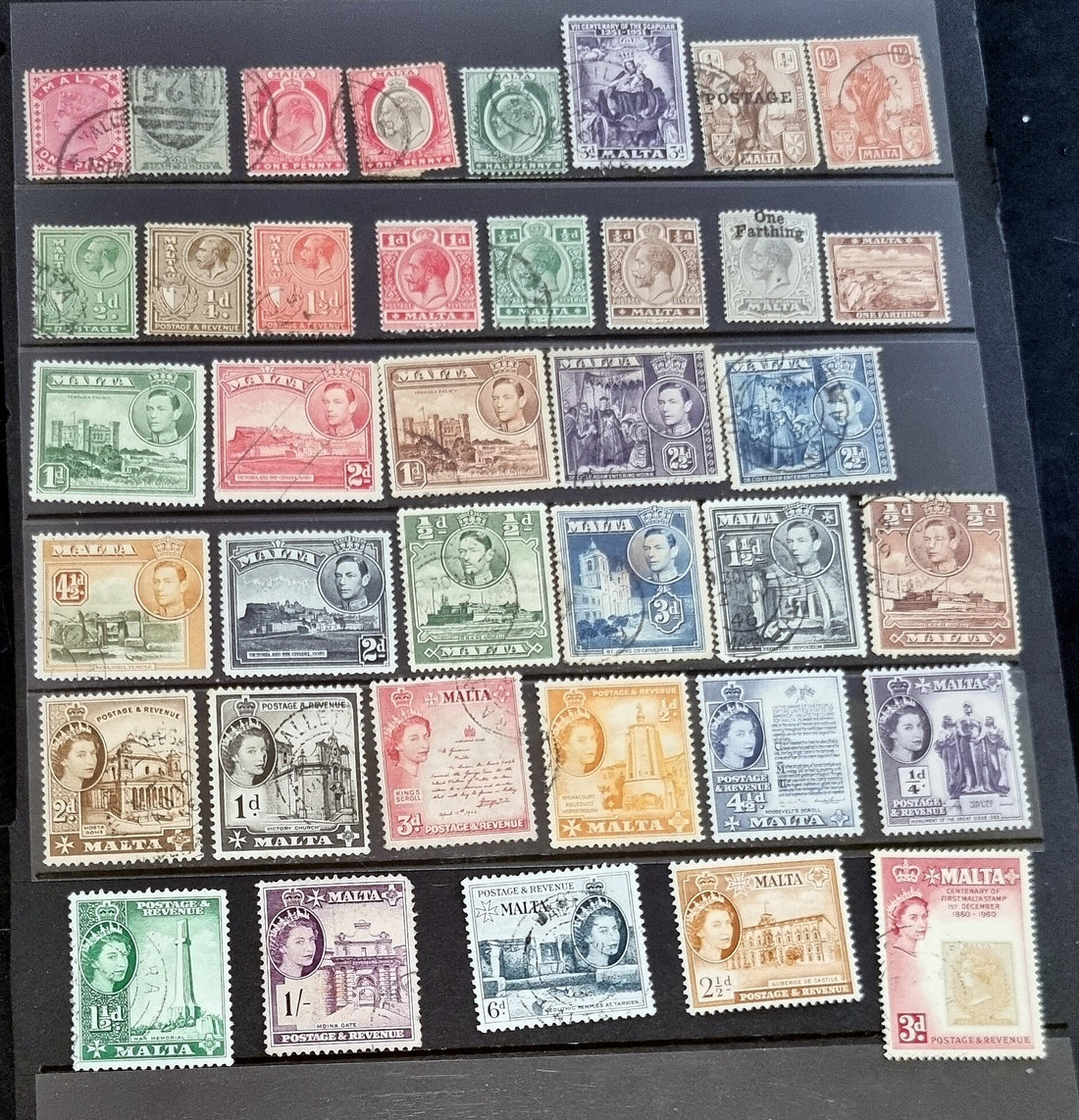 A collection of vintage postage stamps from Malta featuring various designs and colors, arranged in no specific order on a surface.