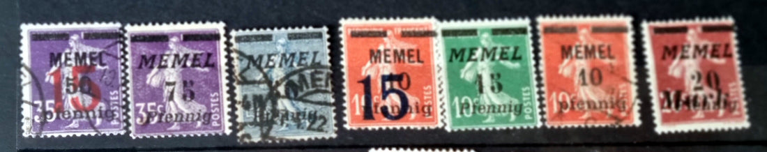 A collection of vintage postage stamps with various colors and designs, including overprinted German stamps with &