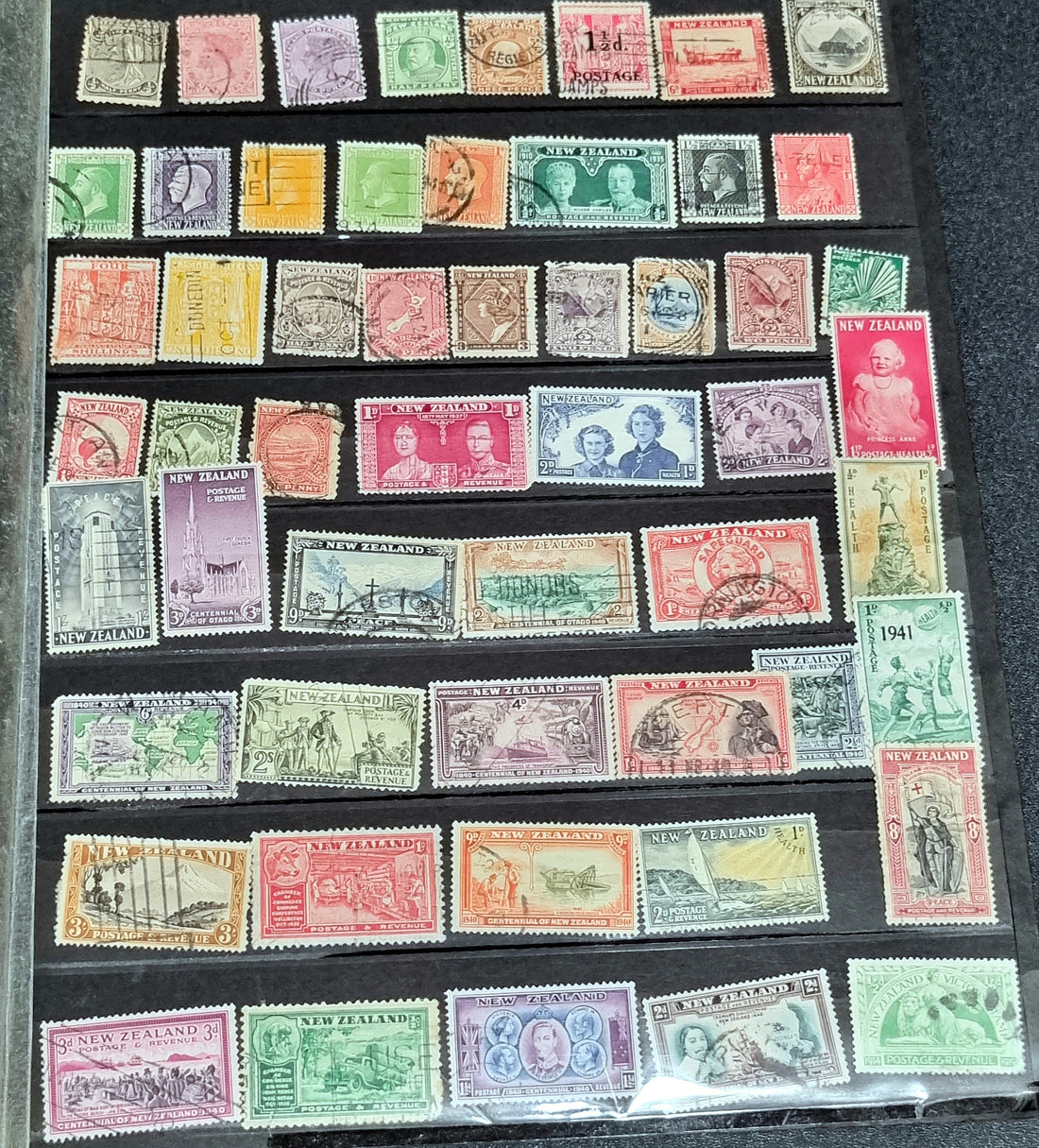 A display of various New Zealand postage stamps, featuring different colors and designs, arranged in rows.